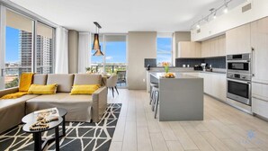 Eine moderne Wohnung mit Wohnbereich, Küche und großen Fenstern mit Blick auf die Stadt.