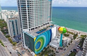 A high-rise hotel with a large mural on the side, a beach ball, and a view of the ocean.