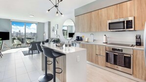 A modern kitchen with a central island, stainless steel appliances, and a city view. - One Bedroom Condo King Bed With City Views (Miami)