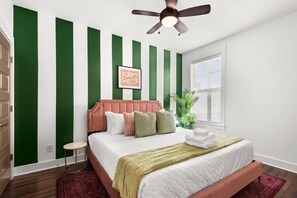 A bedroom with a bed, a ceiling fan, a green and white striped wall, a window, and a plant. - Stunning Influencer House only 5 Mins to Broadway! (Nashville)