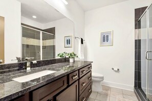 A modern bathroom with a granite countertop, a white sink, a large mirror, a toilet, and a shower area. - Stunning Influencer House only 5 Mins to Broadway! (Nashville)