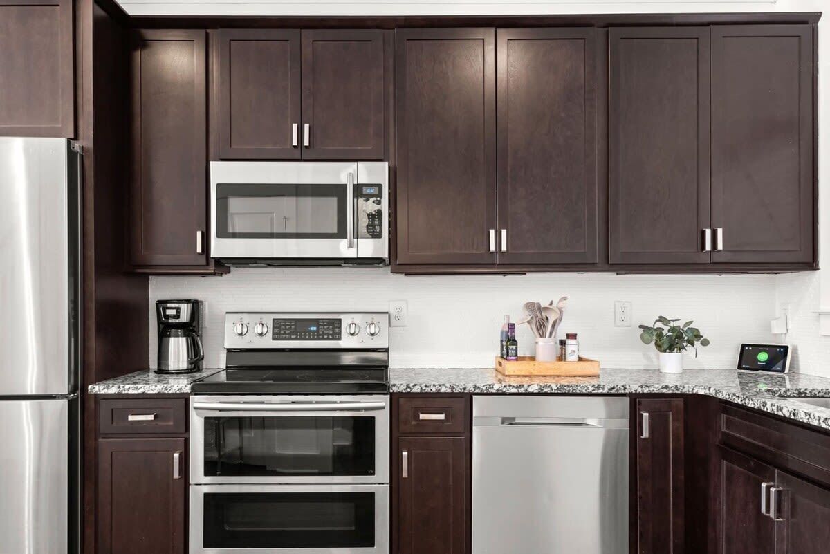 Una cocina moderna con armarios de madera oscura, electrodomésticos de acero inoxidable y una encimera de granito.