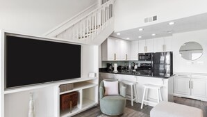 Una cocina moderna con armarios blancos, un refrigerador negro y un televisor de pantalla plana grande.
