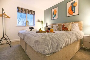 A bedroom with a large bed, a bedside table, a lamp, and a window with a view of trees. - 6 Bedroom House- Free Parking, Fast Wifi & SmartTV (Milton Keynes)