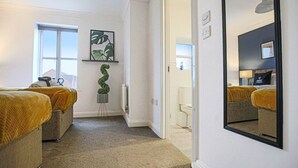 Une chambre d’hôtel avec deux lits, un grand miroir, une plante en pot et une vue sur l’extérieur.