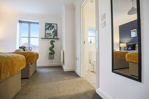 Two single beds, a large mirror, and a potted plant adorn this stylish room.