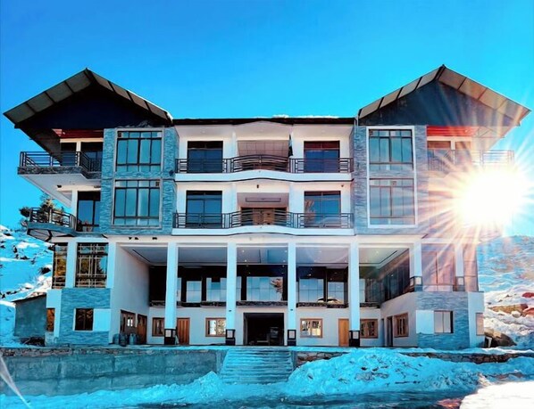 Stunning multi-story building with a central entrance and symmetrical facade, featuring balconies with railings.