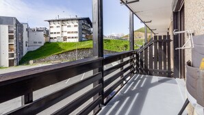 A balcony with a view of a building and a grassy hill. - L'Altitude - Appartement avec balcon au pied des pistes (Saint Lary-Soulan)