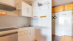 A compact kitchen with white cabinets, a built-in dishwasher, and a microwave. - L'Altitude - Appartement avec balcon au pied des pistes (Saint Lary-Soulan)