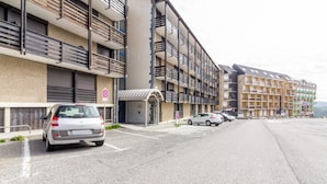 A multi-story hotel with balconies, a parking area, and a no parking sign. - L'Altitude - Appartement avec balcon au pied des pistes (Saint Lary-Soulan)