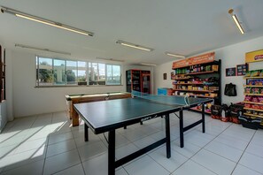Een kamer met een pingpongtafel, een pooltafel en planken vol lekkernijen.