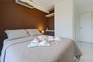 A neatly made bed with towels and toiletries, a bedside lamp, and a door to the right.