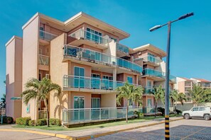 A multi-story hotel with balconies, palm trees, and a paved street.