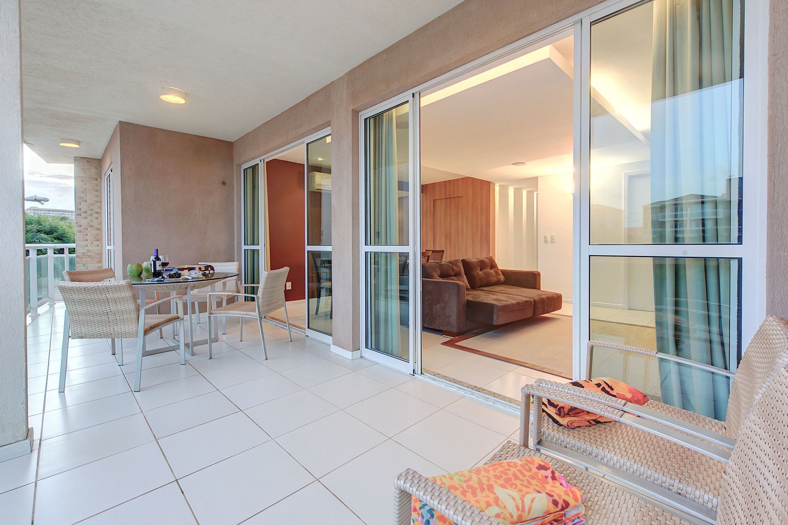 A spacious balcony with a dining area, a sofa, and a view of the interior.