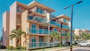 Un hotel de varios pisos con balcones, palmeras y una calle pavimentada.