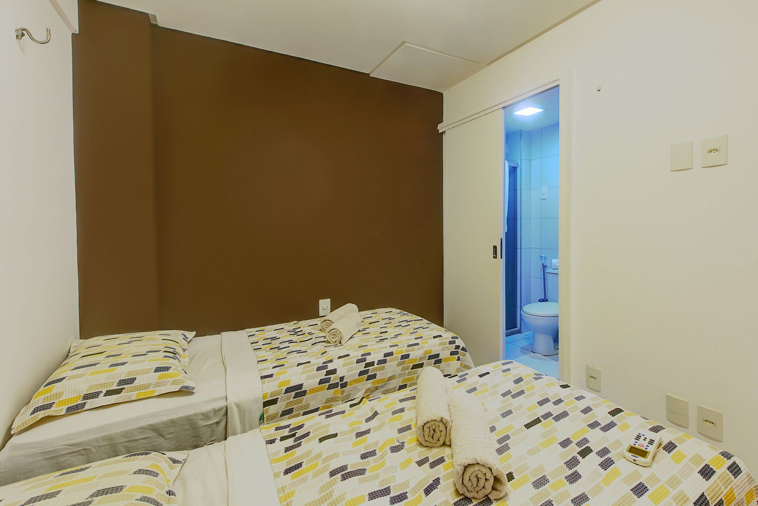 A hotel room with two beds, a brown headboard, and a bathroom visible through an open door.
