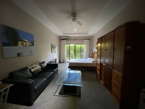 A modern hotel room with a bed, a sofa, a glass coffee table, and a wardrobe.