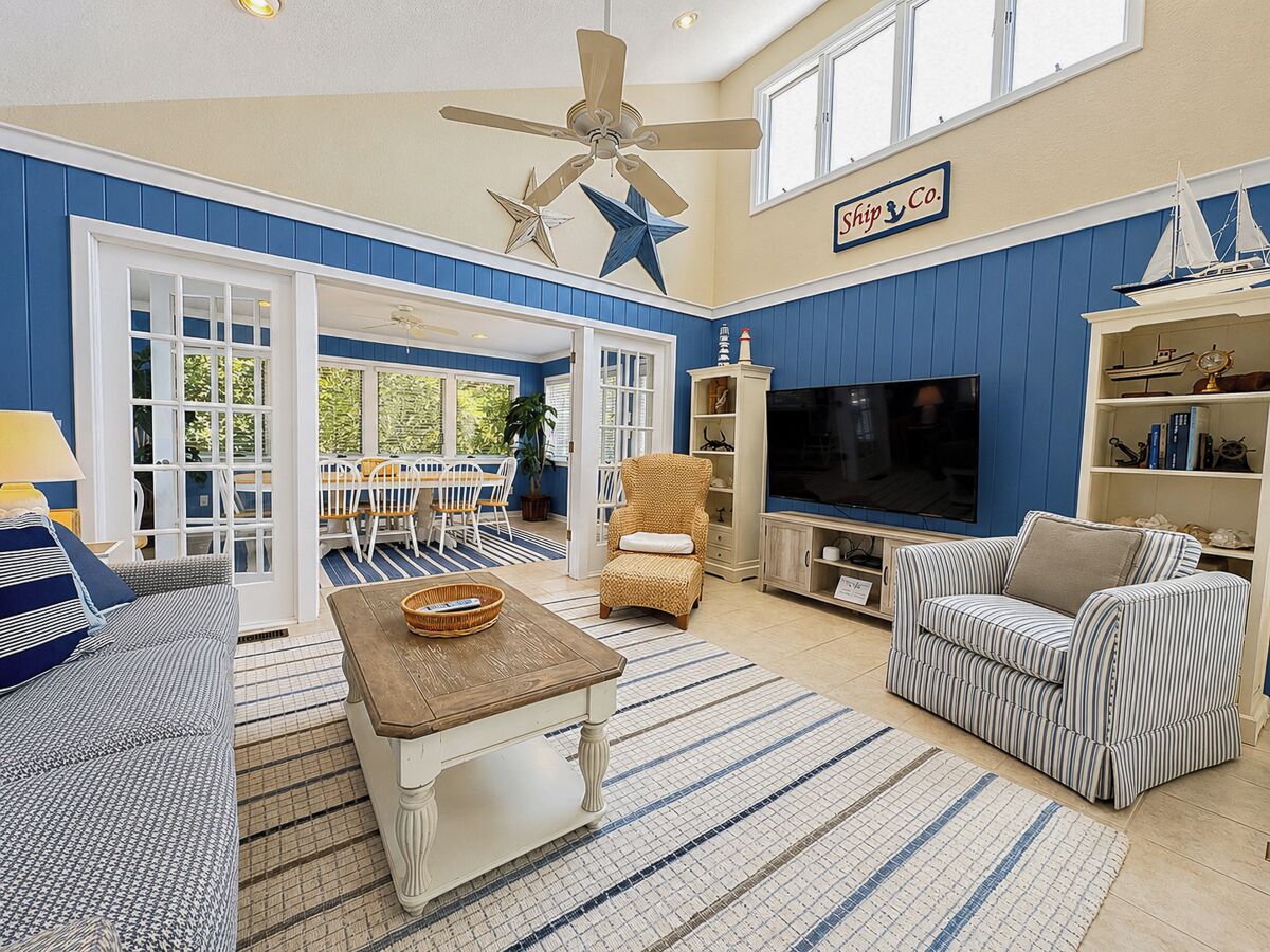 A living room with a TV, sofa, armchair, and a star decoration on the ceiling.