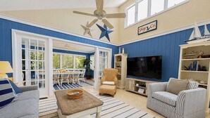 Un salon avec un téléviseur, un canapé, un fauteuil et une décoration en forme d’étoile au plafond.