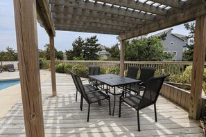 A covered patio with a pool table and chairs, surrounded by a wooden deck and a pool. - 🐾 RAYS HIGH - 5 BR Oceanside home w/ Private Pool & Dog Friendly (Duck)