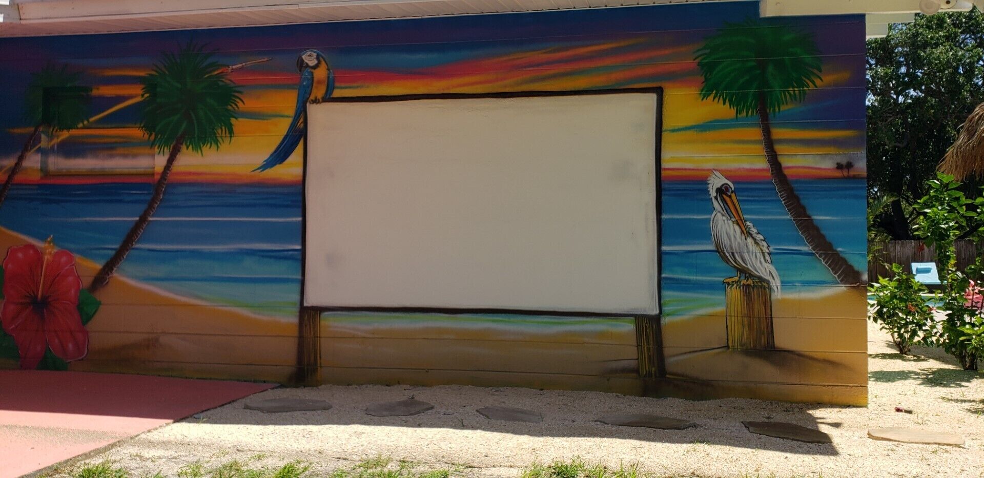 A mural with a beach scene, palm trees, and a bird.