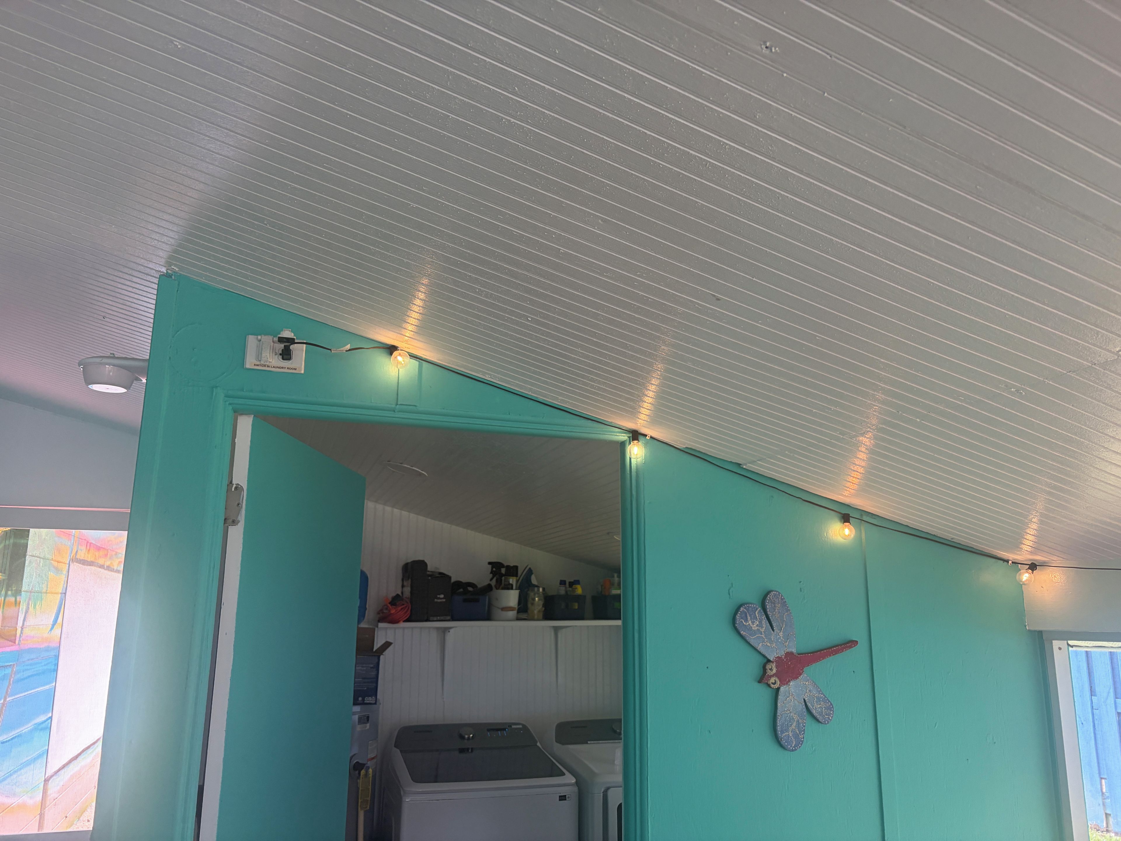 Ein Zimmer mit einer türkisfarbenen Wand, einem Deckenventilator, einer Leuchte und einem an der Wand befestigten Ziergegenstand.