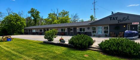 A TAY motel with a covered outdoor seating area, a picnic table, and a well-maintained lawn.