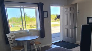 Habitación de hotel con dos camas, una mesa de comedor, sillas, un refrigerador y vistas al exterior.