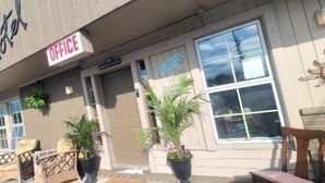 Un motel con un letrero que indica una oficina, asientos al aire libre y plantas en macetas.