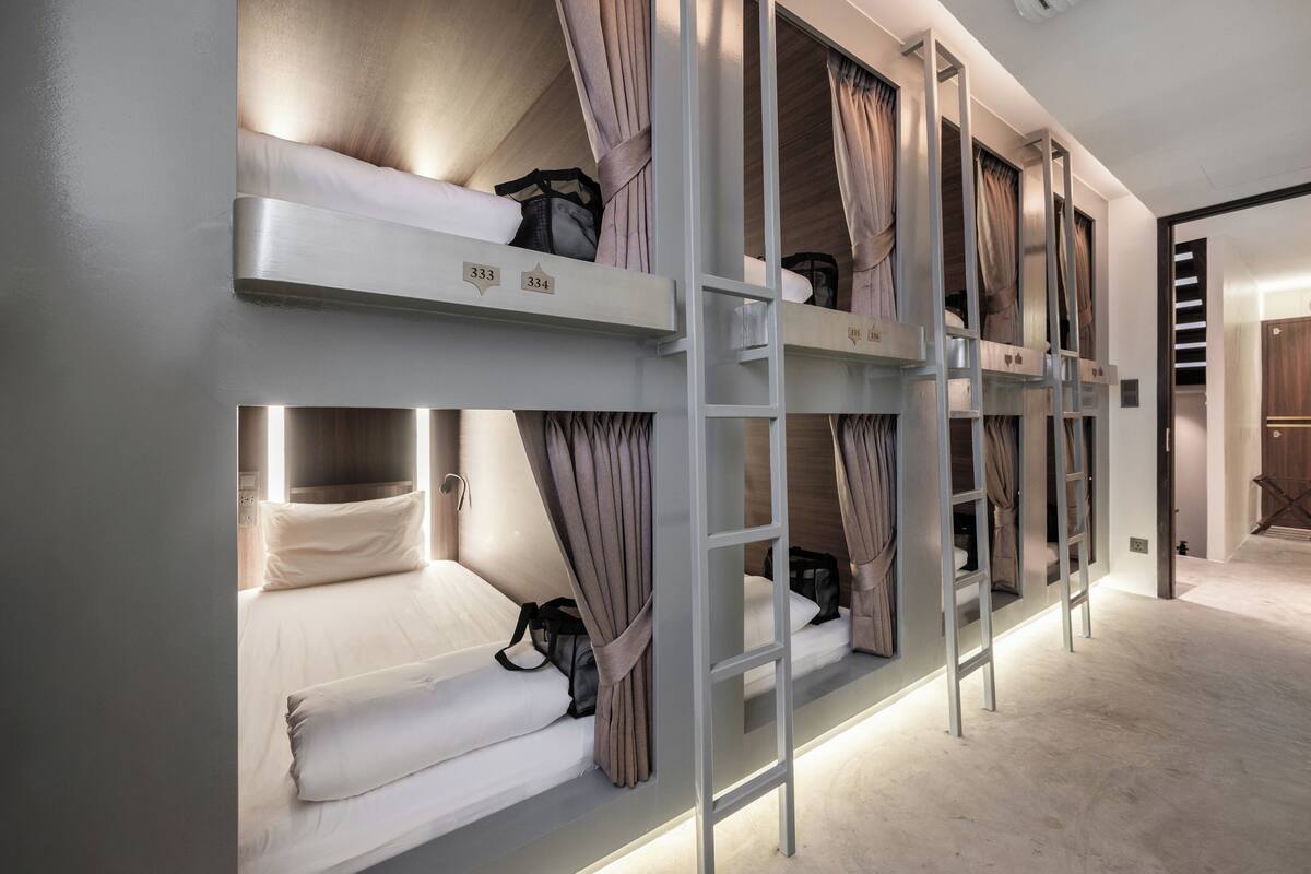 A bunk bed room with a ladder, a wardrobe, and a door leading to another room.