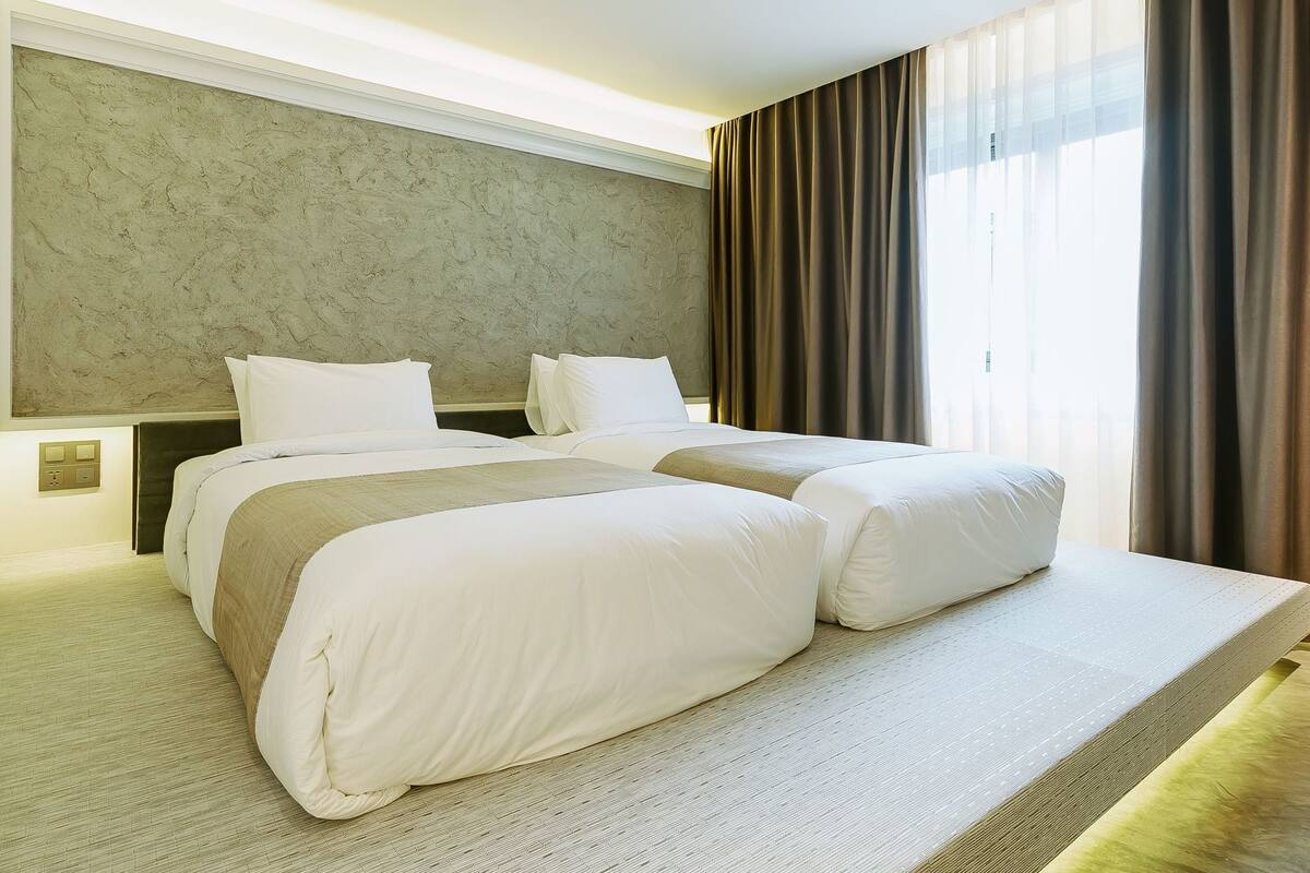 A double bed with white bedding, a headboard, and a bedside table with a lamp.