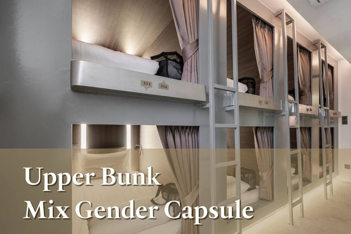 A hotel room with bunk beds, a mix gender capsule, and curtains.