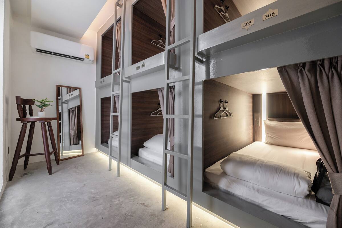 A bunk room with a desk, chair, and hanging clothes rack.