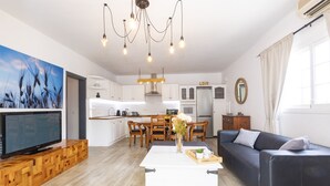 Una sala de estar moderna con un televisor de pantalla plana, una mesa de centro de madera y un sofá negro.