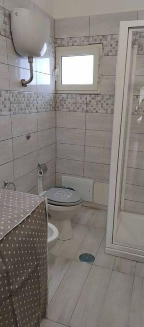 Bathroom with a toilet, shower, and window.