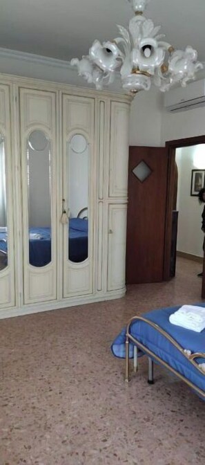 Relax in this traditional bedroom with a large wardrobe, comfortable bed, and elegant chandelier.