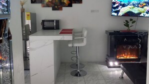 Ein modernes Wohnzimmer mit Marmorboden, einem an der Wand montierten Fernseher, einem Kamin und einer Bar mit Hockern.