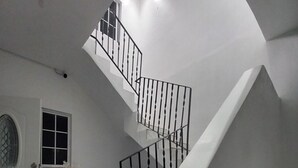 Ein modernes Interieur mit Treppe, einer weißen Tür mit Glasfenster und einem Fliesenboden.