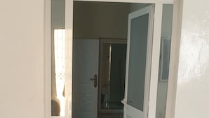 A room with a marble floor, a beige sofa, and a door leading to another room.