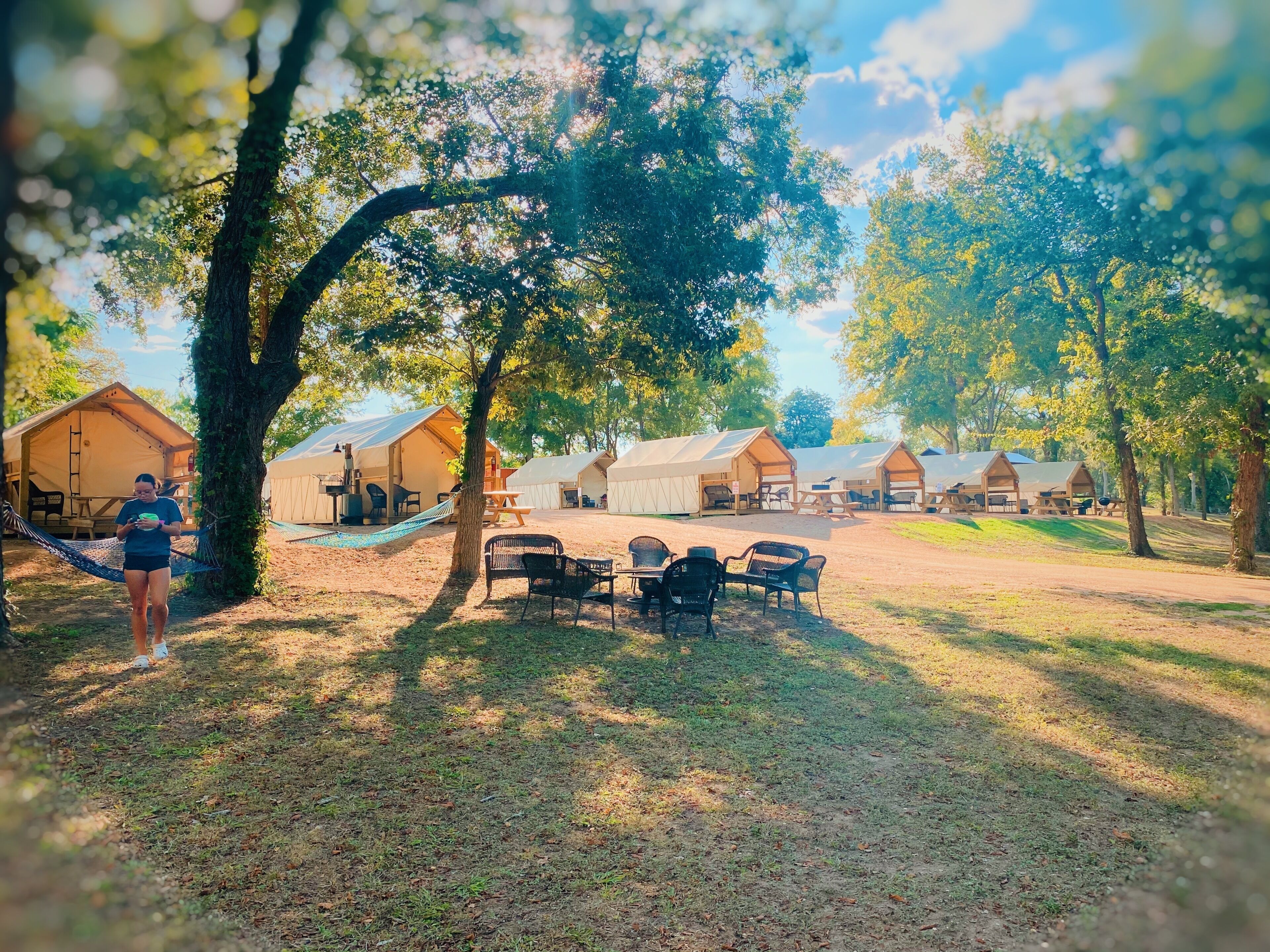 En campingplats med flera tält, picknickbord och en hängmatta.