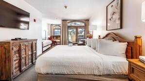 Una camera d'albergo con un letto grande, un armadio in legno, una scrivania e un televisore.