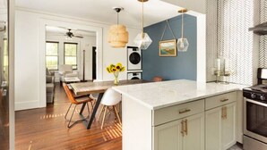Une cuisine moderne dotée d’un îlot en marbre, de luminaires suspendus et d’un pare-feu décoratif.
