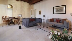 A living room with a dining table, two sofas, a coffee table, and a chandelier.