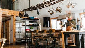 Une cuisine rustique avec des poutres en bois, des ustensiles de cuisine suspendus et un mur en pierre.