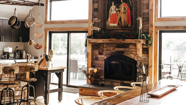 Une cuisine spacieuse avec un grand îlot central, des chaises en bois et une cheminée en pierre.