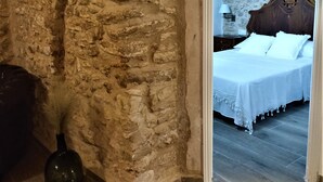 A rustic room with a stone wall, a bed with white linens, and a wooden floor. - Rural tourist apartment with spa area. Main Square. PB. Sant Jordi (Sant Jordi)