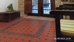 A room with a stone wall, wooden double doors with metal bars, a patterned red carpet, and a painting on the wall. - Rural tourist apartment with spa area. Main Square. PB. Sant Jordi (Sant Jordi)