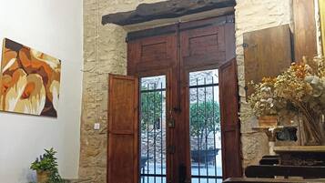 Una habitación con pared de piedra, puertas dobles de madera con barrotes de metal, alfombra roja estampada y un cuadro en la pared.