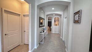 A hallway with white doors, a console table with decorative items, and a framed mirror on the wall.