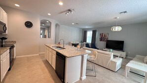 A modern kitchen with granite countertops, a built-in dishwasher, and a central island with a sink.